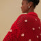 up close of model wearing red open knit crochet sweater with balloon sleeves, collar and small pink appliques