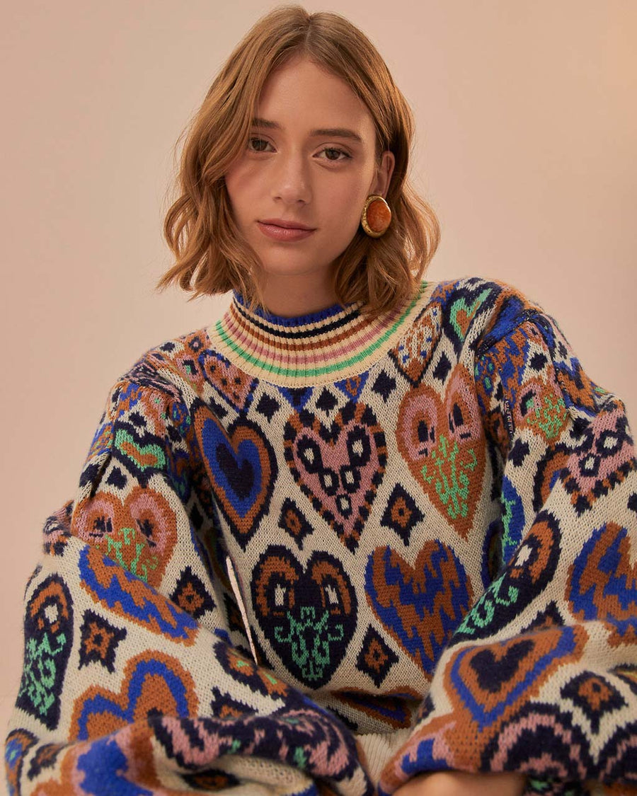 up close of model wearing sand ground with colorful ikat and heart pattern with rainbow stripe mock neckline and bottom hem