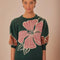 model wearing green short sleeve sweater with burnt rust and pink flower print