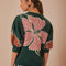 back view of model wearing green short sleeve sweater with burnt rust and pink flower print