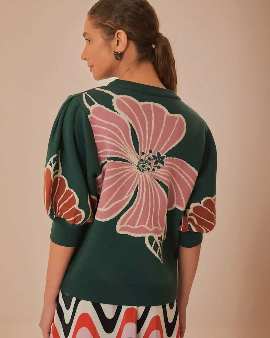 back view of model wearing green short sleeve sweater with burnt rust and pink flower print