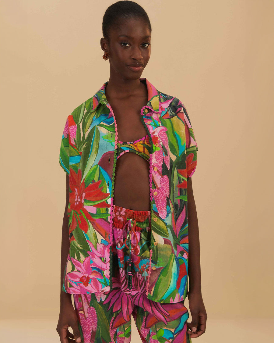 model wearing colorful tropical floral print with button front and pink and green mini tassel detail on the placket and sleeves