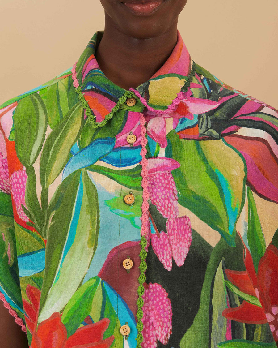 model wearing buttoned colorful tropical floral print with button front and pink and green mini tassel detail on the placket and sleeves