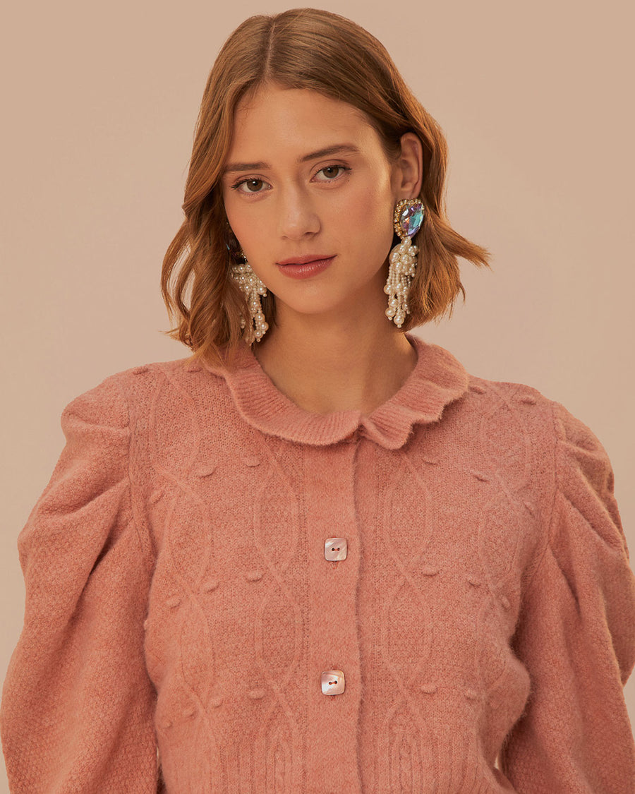 up close of model wearing light pink cardigan with button front, ruched sleeves with ruffle detail and slight scalloped collar