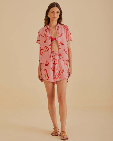 model wearing pink shorts with elastic waist, pom leg detail and all over lobster print 