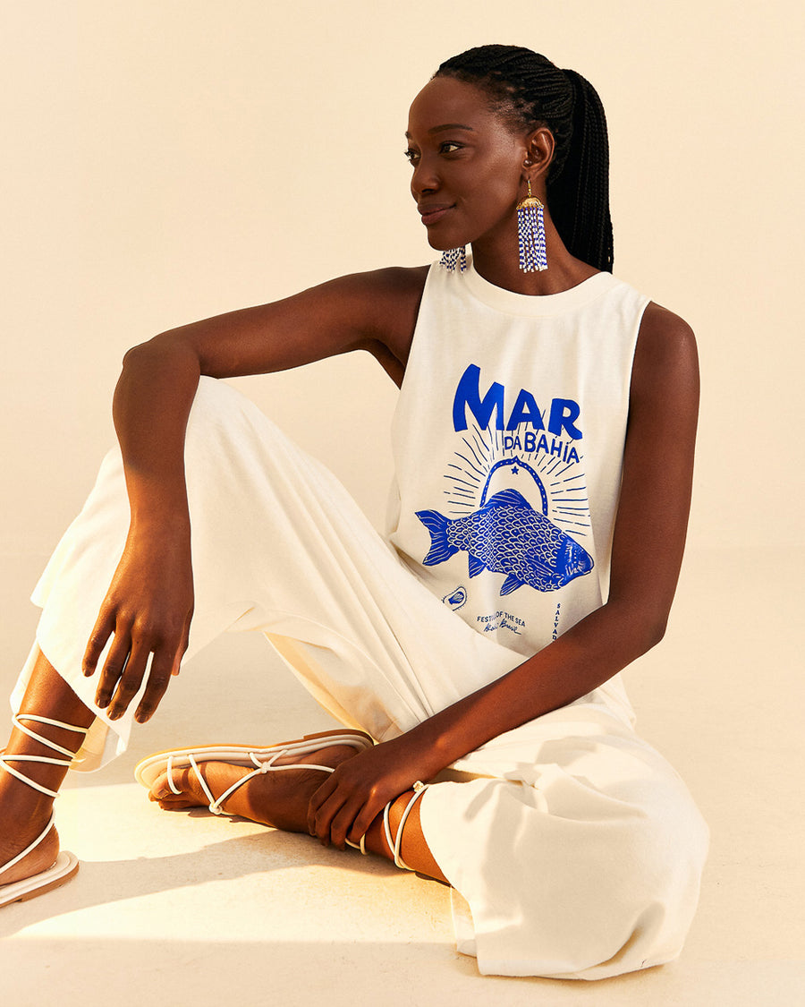 model wearing cream cotton jumpsuit with blue 'mar da bahia' and fish graphic on front