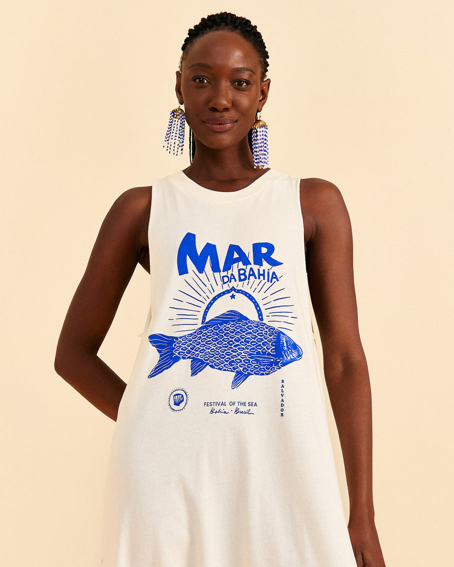 up close of model wearing cream cotton jumpsuit with blue 'mar da bahia' and fish graphic on front