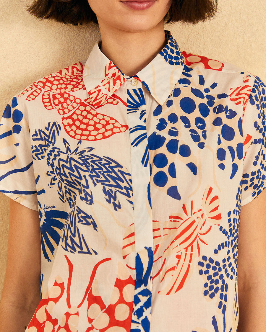 up close of model wearing off white short sleeve button down top with blue and red abstract lobster print