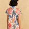 backview of model wearing off white short sleeve button down top with blue and red abstract lobster print