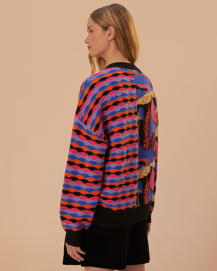 back view of model wearing split cardigan with blue abstract mushroom print and red, blue and black wavy print