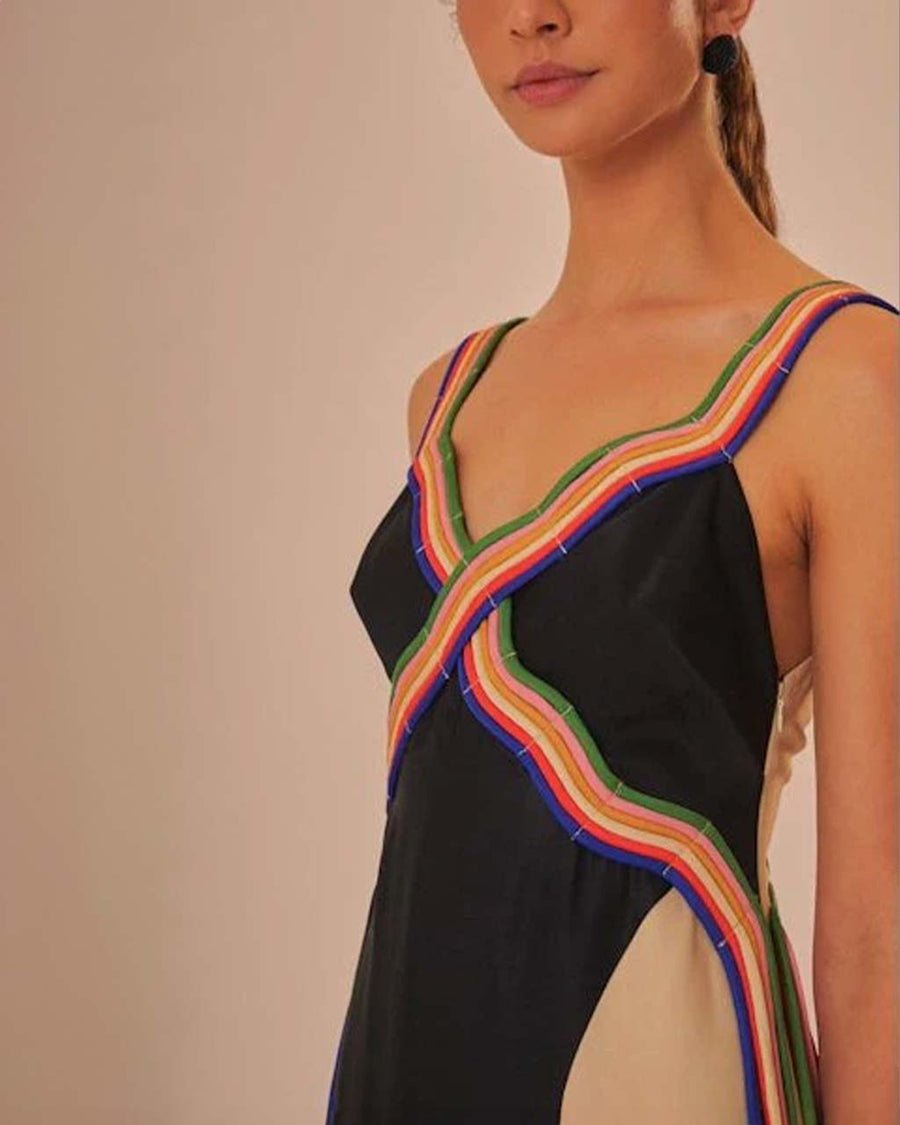 up close of model wearing black midi dress with cream face silhouette on the side and colorful rope trim along the straps and bodice