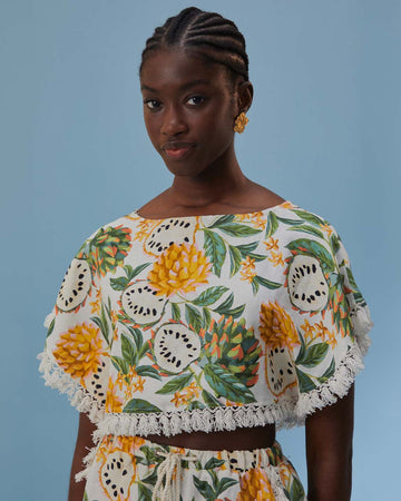 model wearing white crop top with fringe detail and mixed fruit print