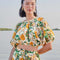 model wearing white cropped blouse with mixed fruit print  and slight puff sleeves