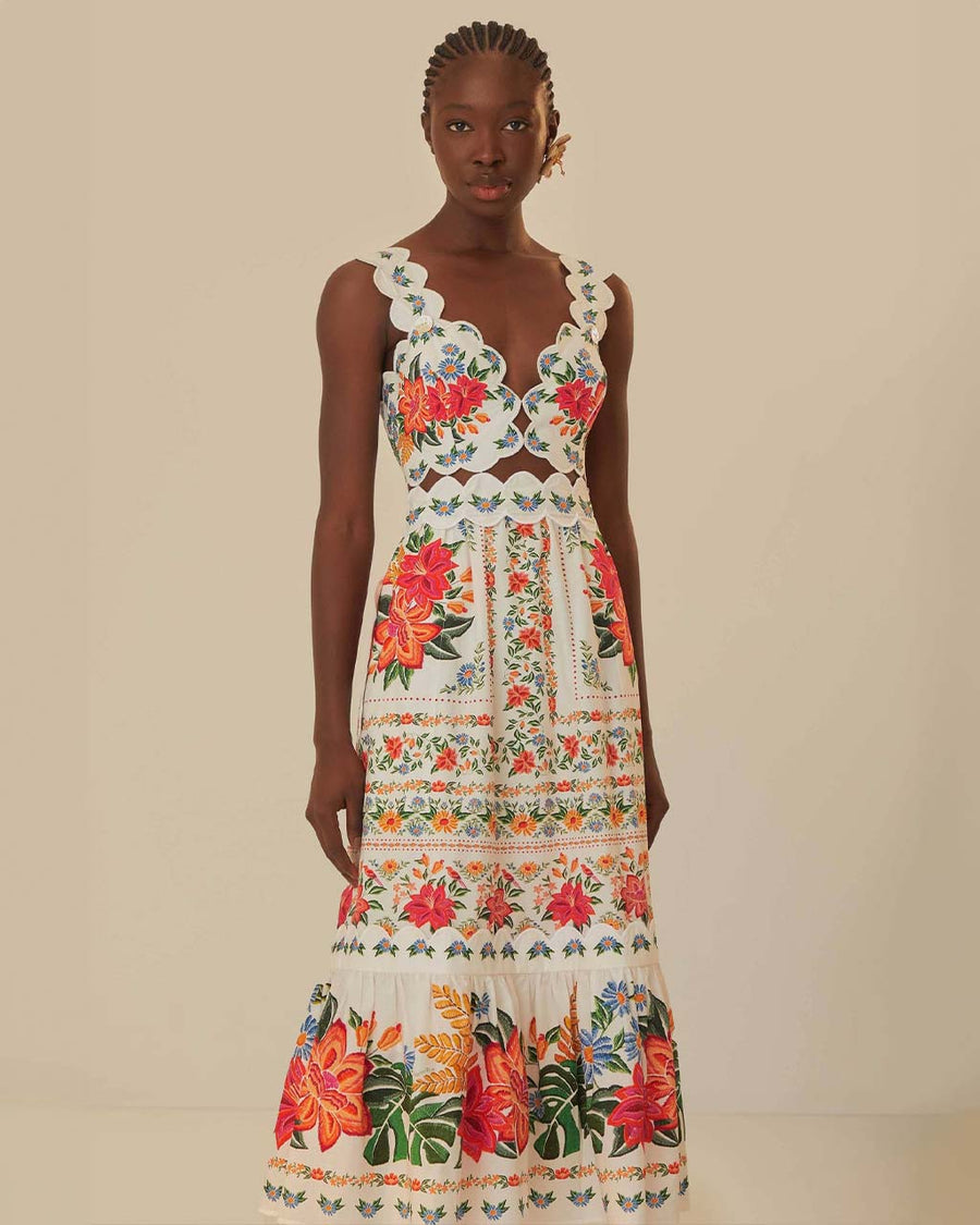 model wearing white midi dress with scalloped bodice and straps , cut out waist, and all over colorful floral print