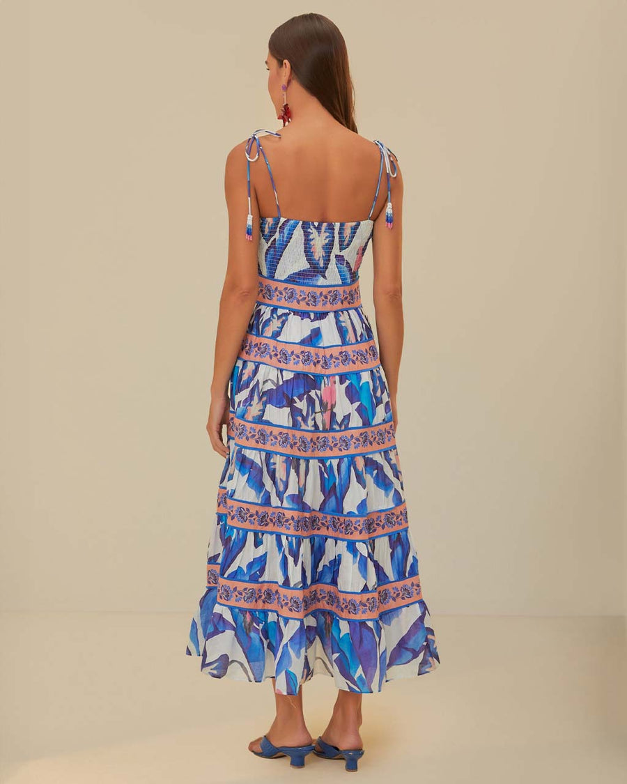 back view of model wearing white midi dress with blue foliage print, pink floral stripes, and tie straps with beaded ends