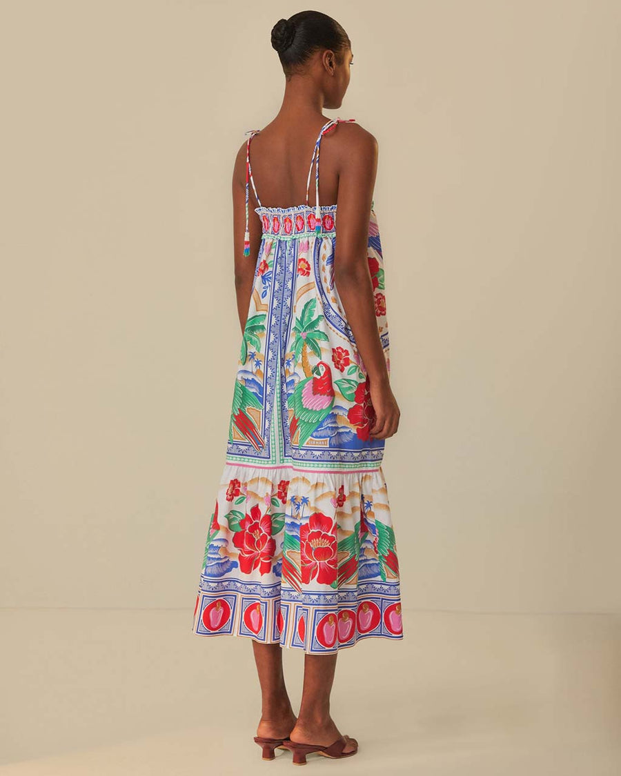 back view of model wearing white maxi dress with abstract tropical print with parrots