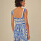 back view of model wearing blue and white title print romper with button front, smocked back, and tie waist