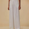 model wearing white wide leg linen pants with gold belt detail