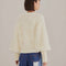 back view of model wearing textured off white slight cropped cardigan with with blouson sleeves 