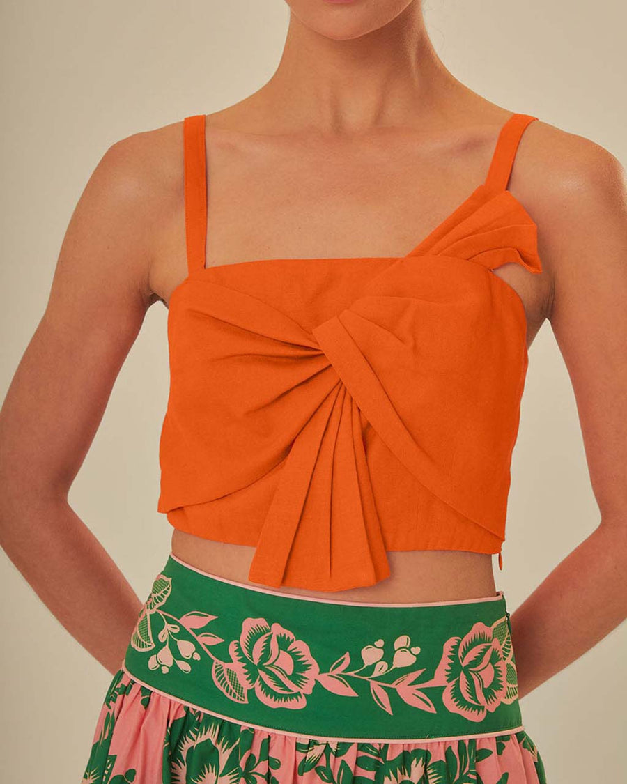 up close of model wearing orange cropped tank with bow front detail on bust