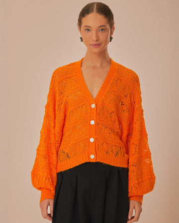 model wearing orange open knit textured cardigan with slight puff sleeves and fashion button front