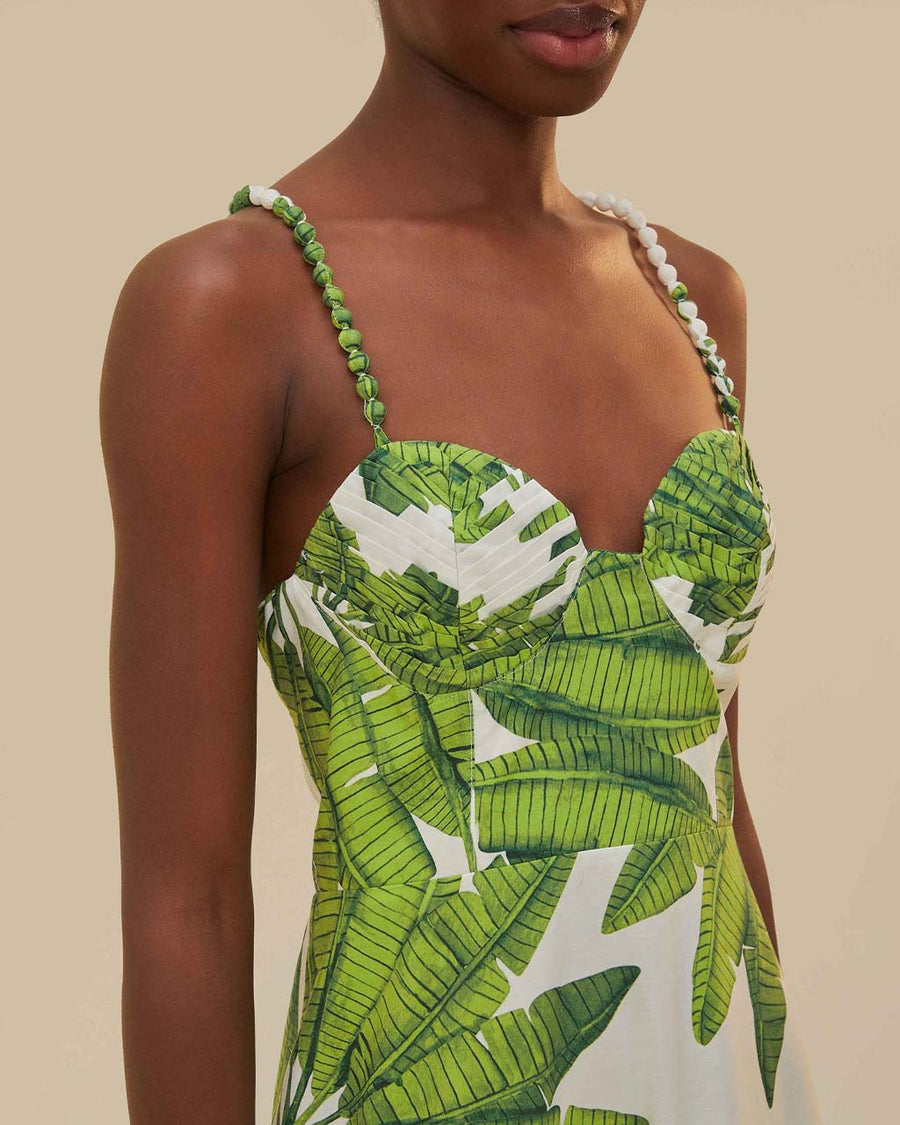 up close of model wearing white midi dress with corset bust, textured straps and green palm leaf print