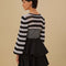 back view of model wearing black and white striped crochet top with long, flared sleeves