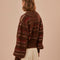 back view of model wearing brown cropped cardigan with puff sleeves and red and cream woven stripe design