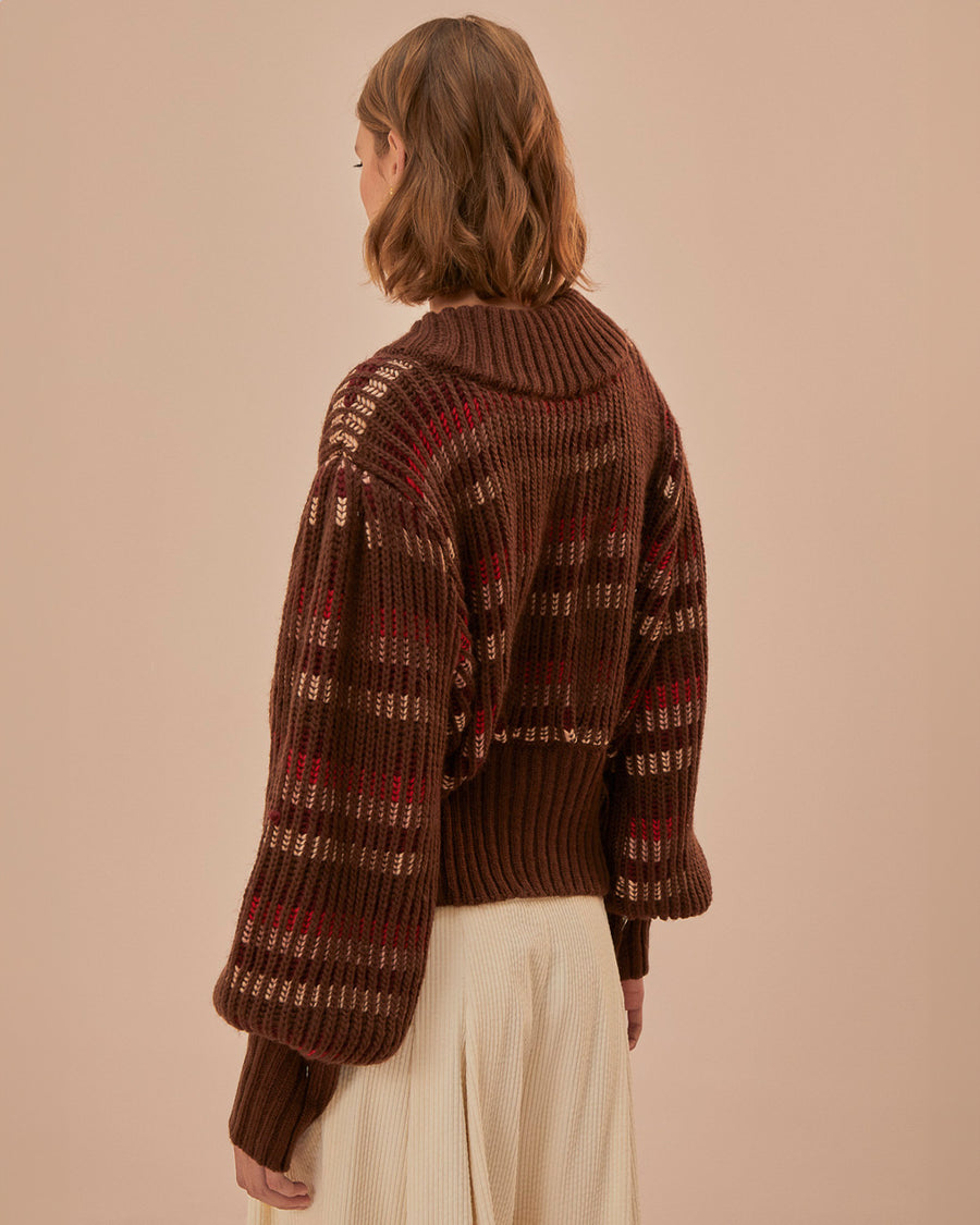 back view of model wearing brown cropped cardigan with puff sleeves and red and cream woven stripe design