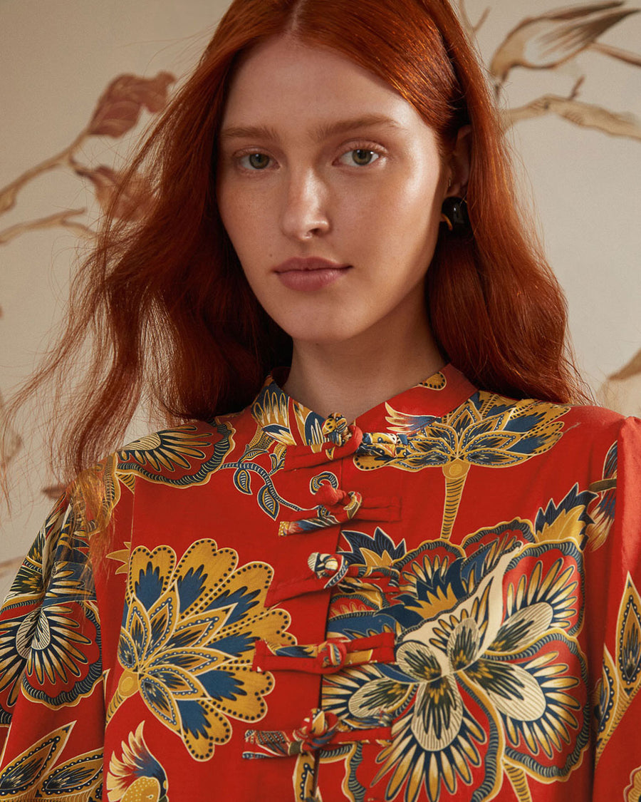 up close of model wearing red long sleeve mini dress with all over floral print and toggle button front detail