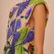 sideview of model wearing sand t-shirt dress with colorful tropical print and tie waist