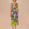 model wearing sand midi dress with deep v neckline and all over colorful tropical print