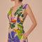 side view of model wearing sand midi dress with deep v neckline and all over colorful tropical print