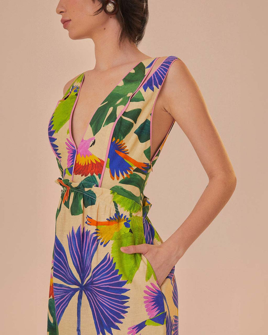 side view of model wearing sand midi dress with deep v neckline and all over colorful tropical print