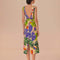 back view of model wearing sand midi dress with deep v neckline and all over colorful tropical print