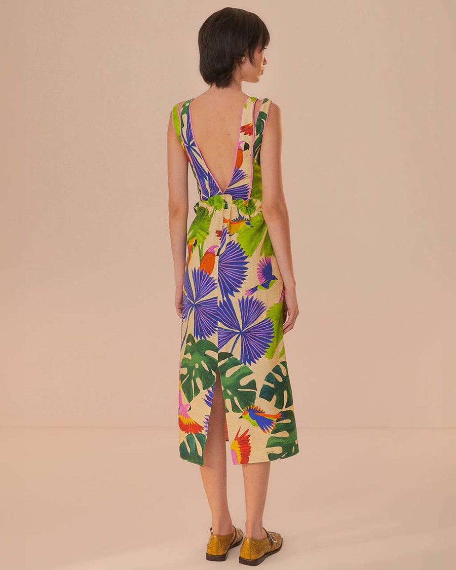 back view of model wearing sand midi dress with deep v neckline and all over colorful tropical print