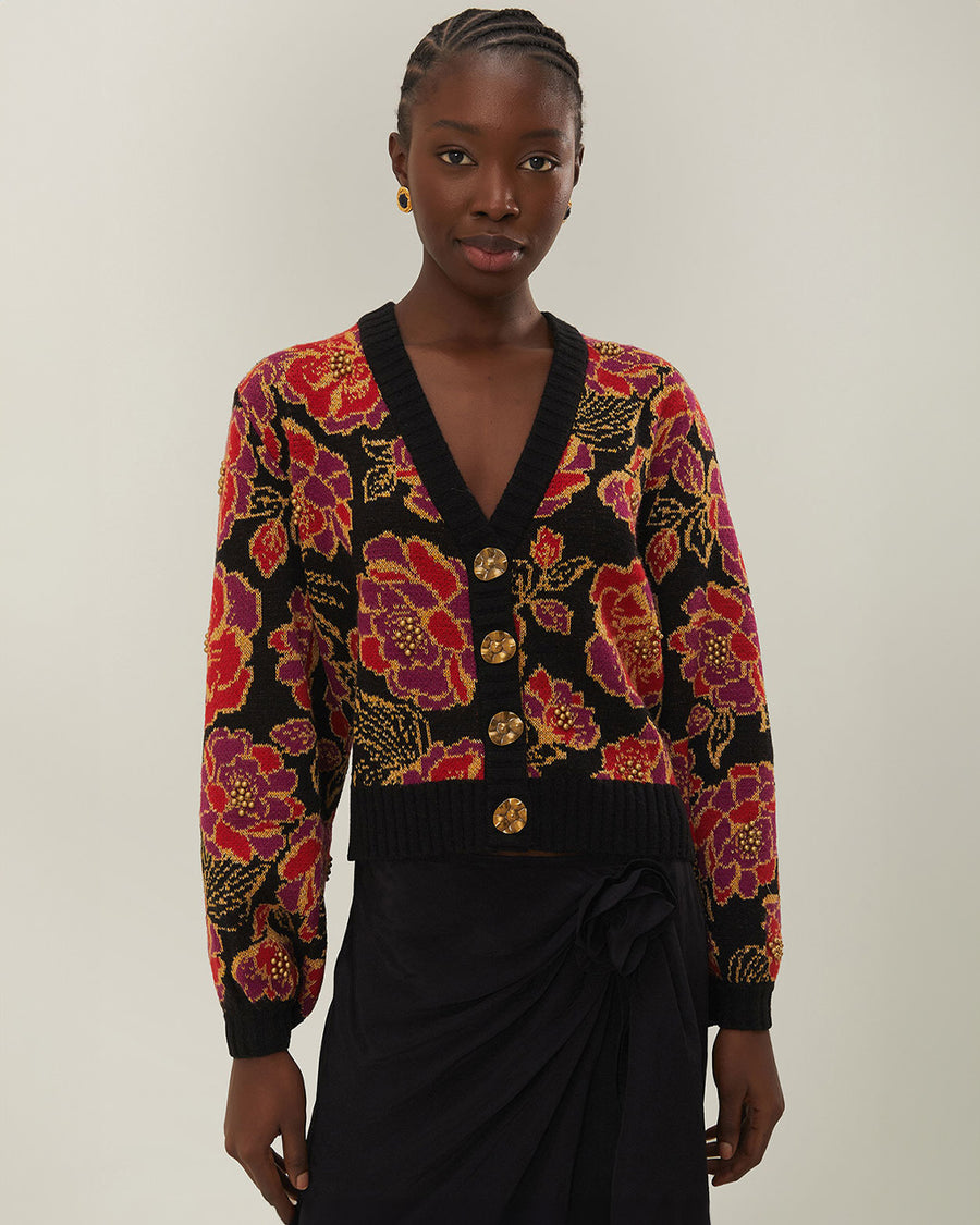 model wearing black cropped cardigan with red and purple flowers, gold beading and gold decorative buttons