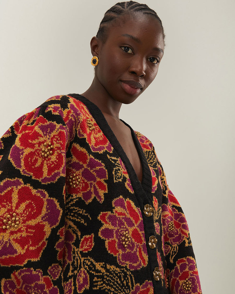 model wearing black cropped cardigan with red and purple flowers, gold beading and gold decorative buttons