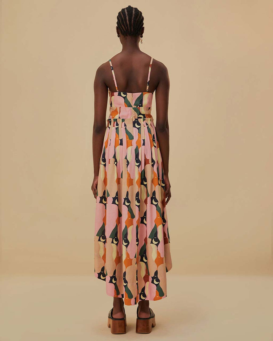 back view of model wearing pink midi dress with curved hem, corset bodice, and colorful abstract print