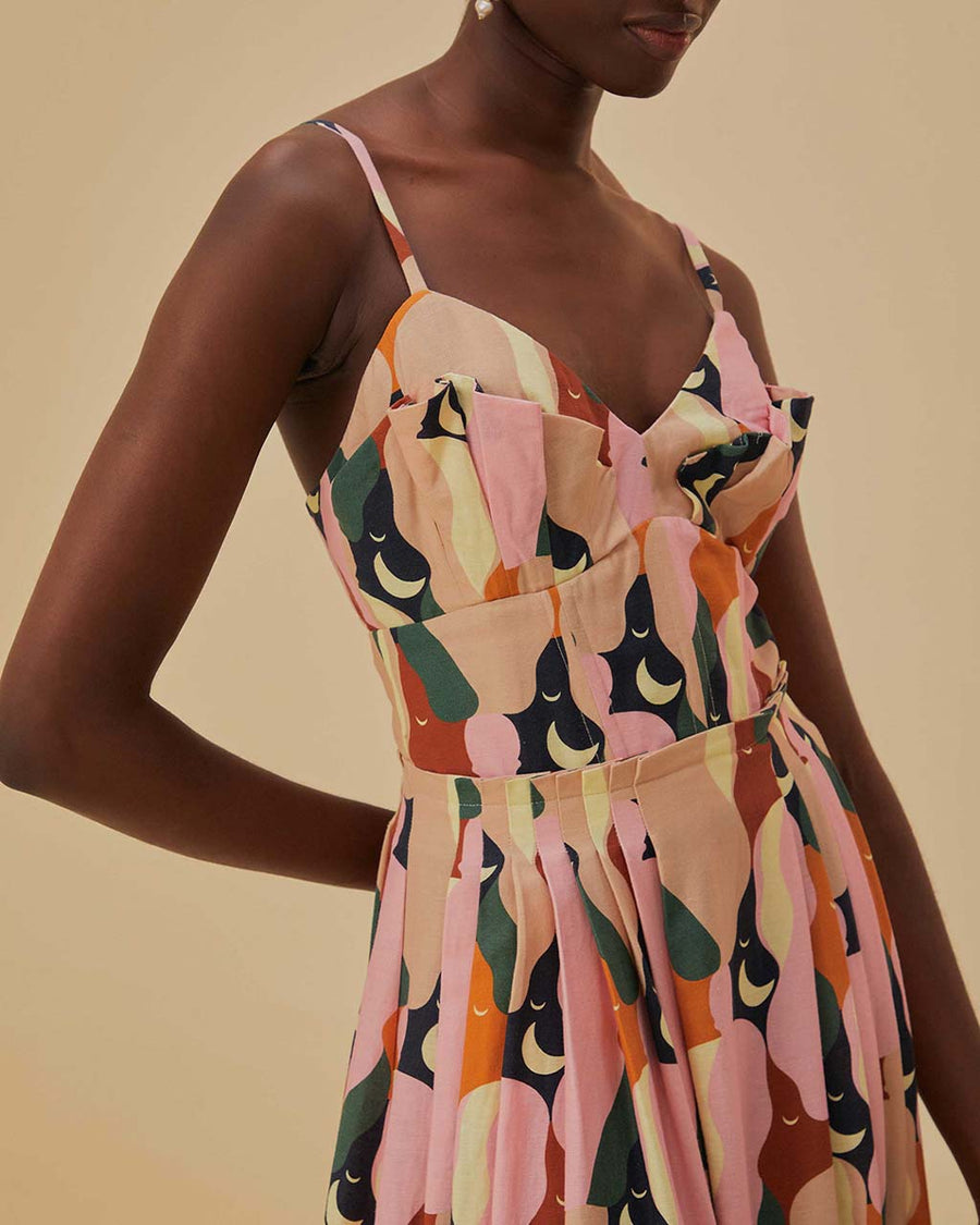 up close of model wearing pink midi dress with curved hem, corset bodice, and colorful abstract print