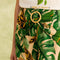 up close of model wearing nude shorts with tropical leaf print, bamboo belt, and white pepper tee