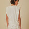 back view of model wearing white muscle tank top with beaded fruit detail around the neckline