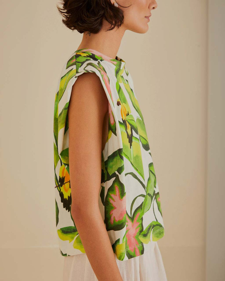 side view of model wearing off white square shoulder top with green tropical leaf print