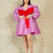 model wearing metallic lavender dress with flowy skirt, oversized sleeves and collar and large red bow on the front