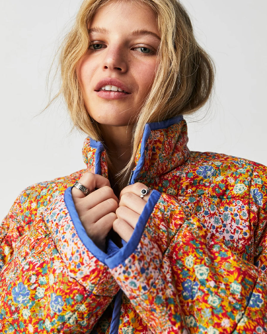 up close of model wearing colorful floral quilted jacket with periwinkle piping and trim