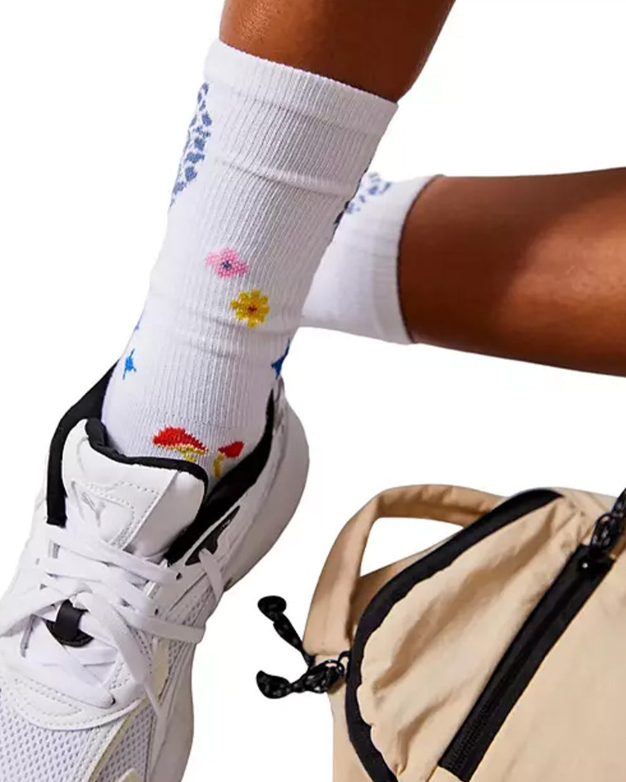 model wearing white long crew socks with colorful leaves, floral and mushroom print with white sneakers on