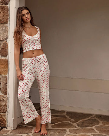 model wearing cream lounge set with cropped with ruched tank and pants with red floral print