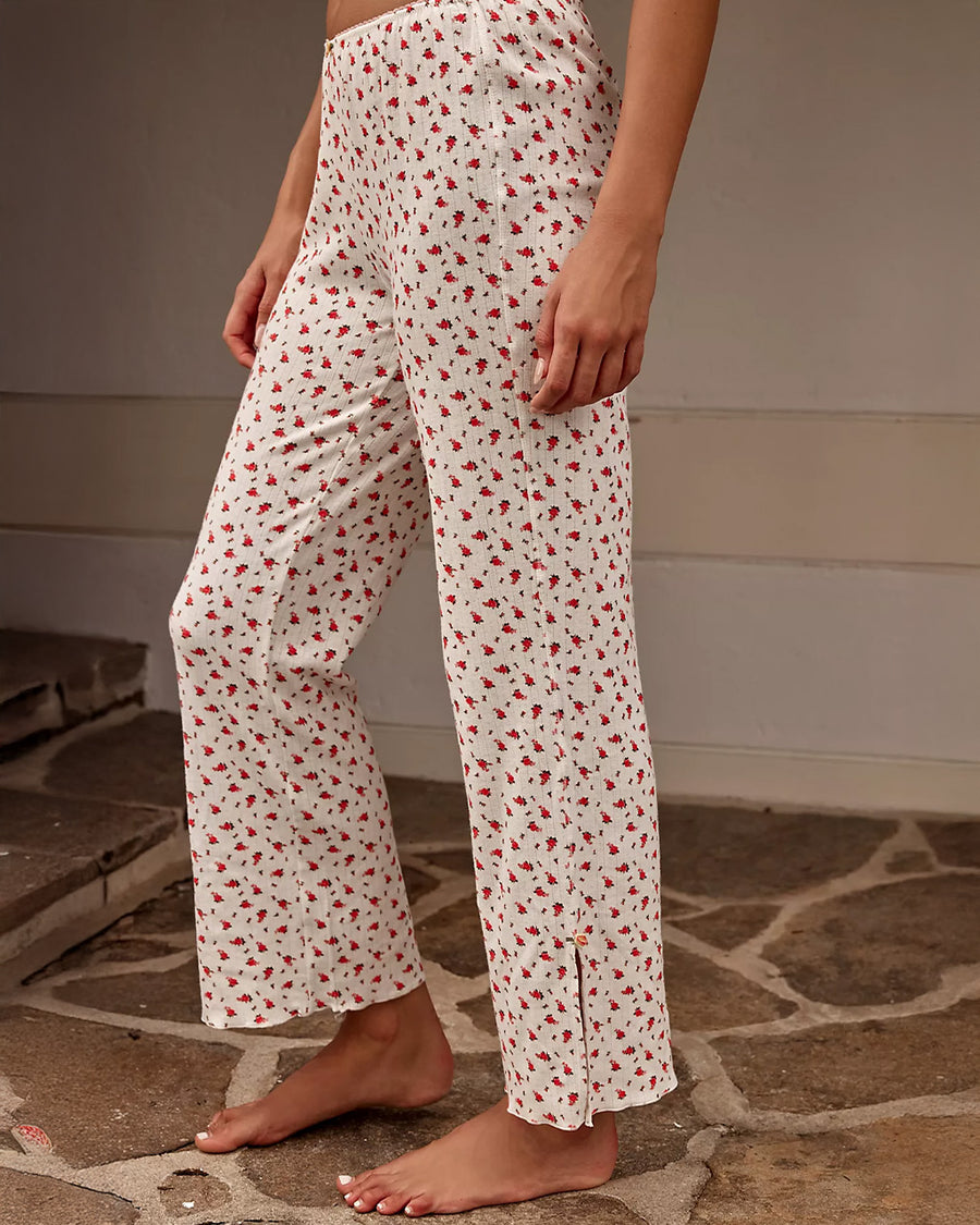 model wearing cream lounge  pants with red floral print and slits on the legs