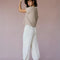 back view of model wearing sweater set with tan knit short sleeve sweater with front pocket on bust and cream balloon pants with pockets