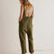 back view of model wearing moss green jumpsuit with adjustable straps and patch front pockets